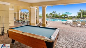 A pool table in an outdoor area with a pool and lounge chairs. - The Epic 36208 Lake View Vista Cay Resort Orlando Florida (Orlando)