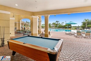A pool table in an outdoor area with a pool and lounge chairs. - The Epic 36208 Lake View Vista Cay Resort Orlando Florida (Orlando)