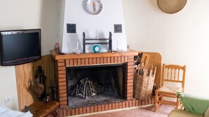 Ein Wohnzimmer mit Kamin, Fernseher, einer Holzbank und einem Sessel.