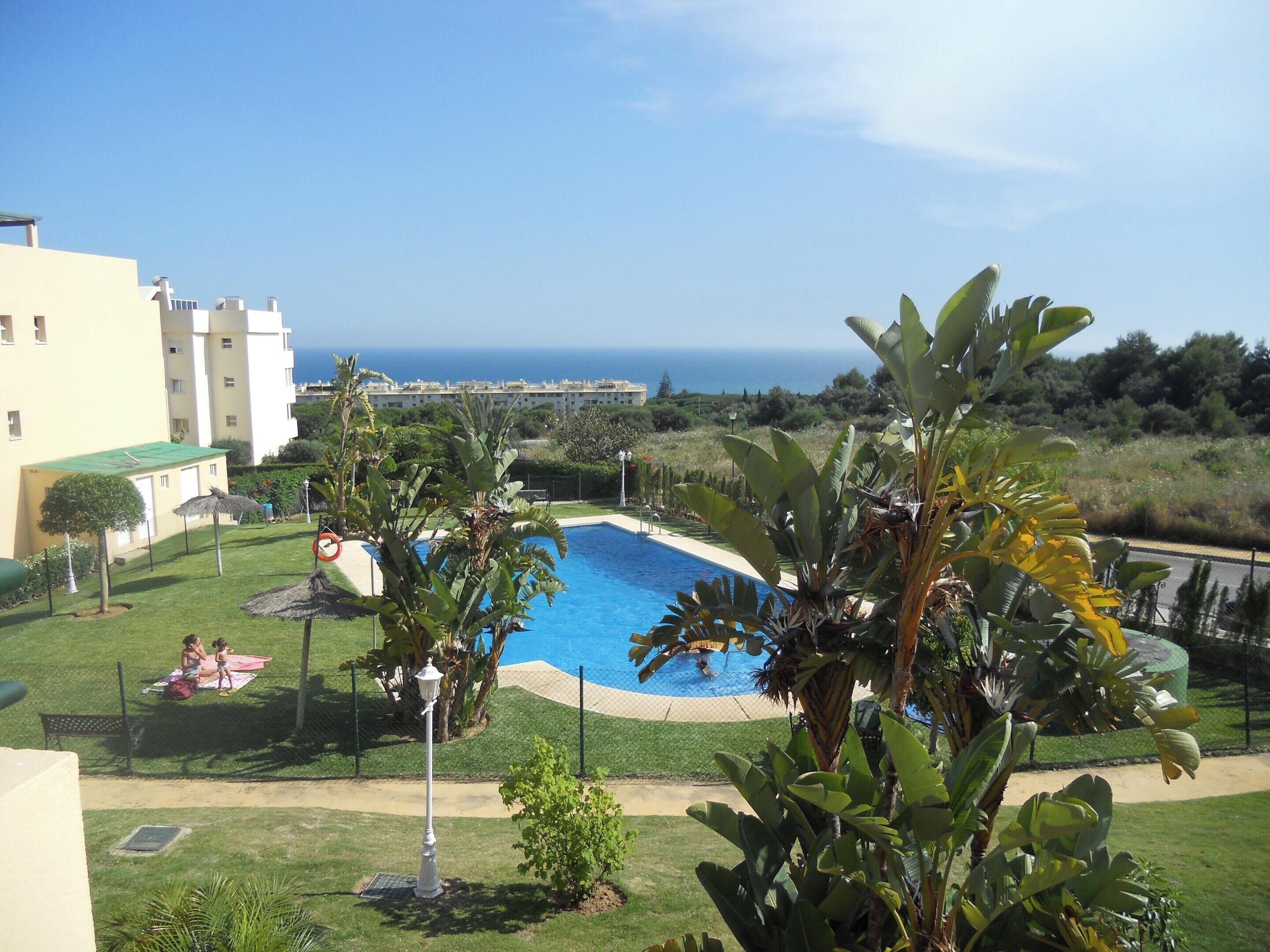 Une piscine entourée d’une végétation luxuriante, avec vue sur la mer.