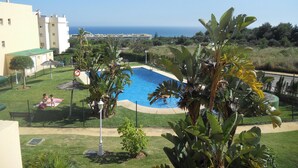 Ein Schwimmbecken, umgeben von üppiger Vegetation mit Blick auf das Meer.