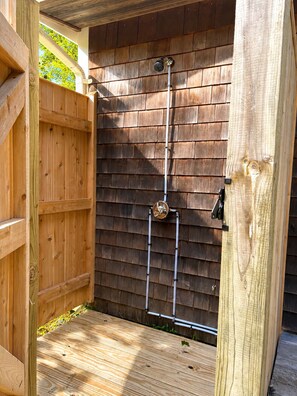 Une structure extérieure en bois équipée d’un système de douche en métal.