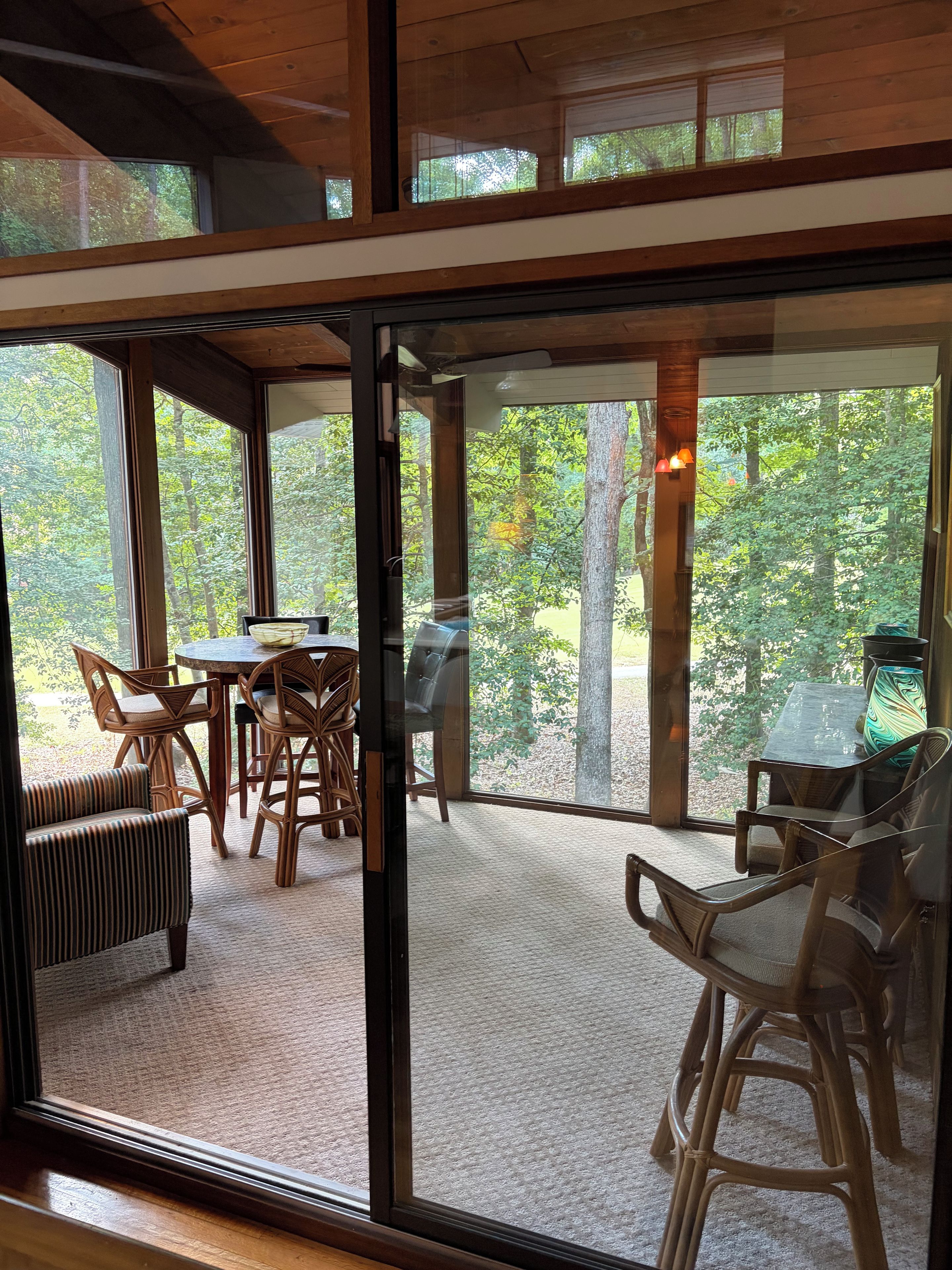 A room with a large glass door leading to an outdoor area with a table and chairs.