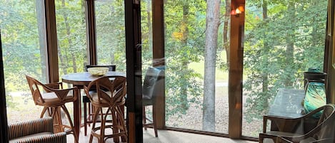 A room with a large glass door leading to an outdoor area with a table and chairs.