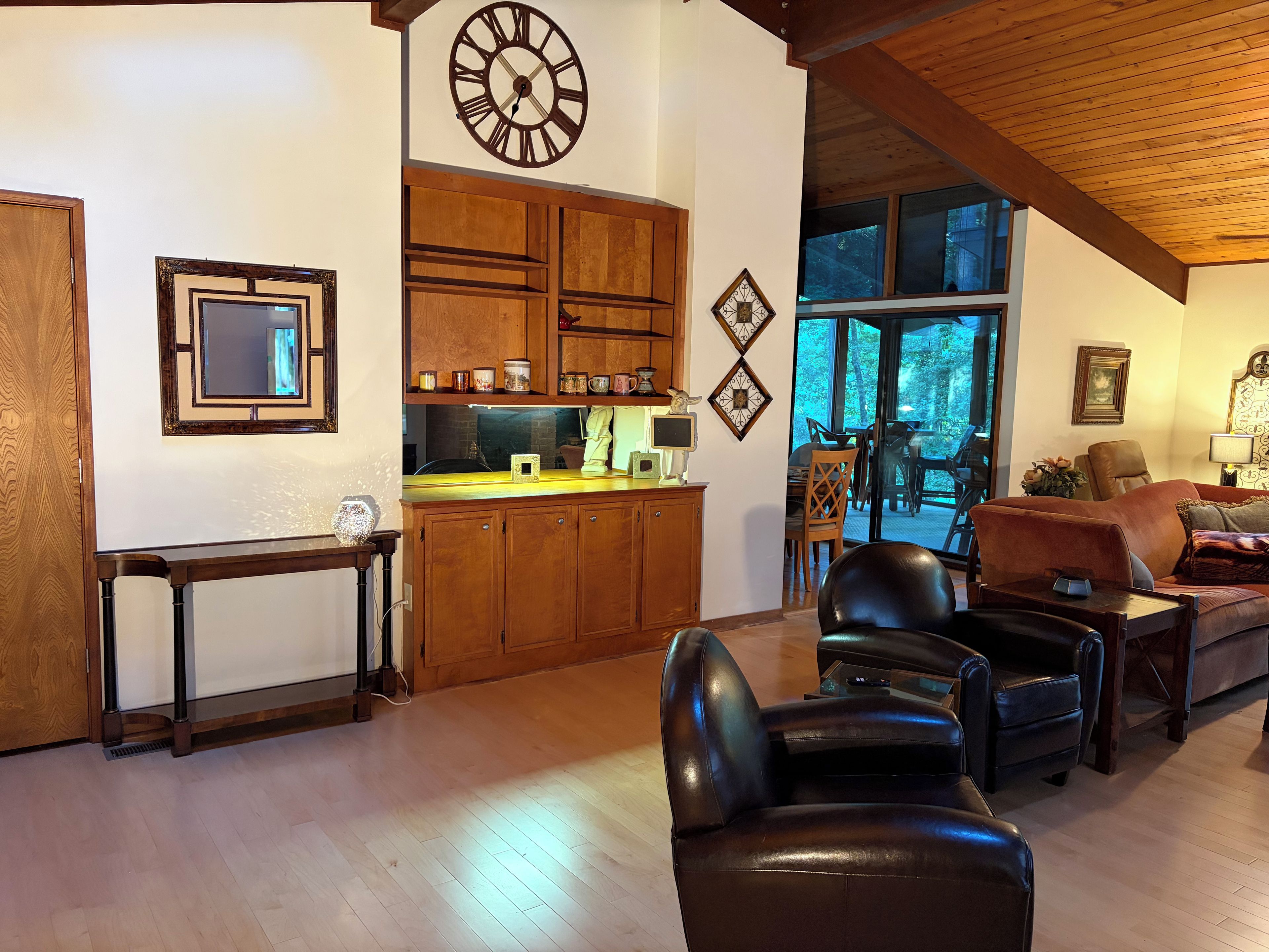 Een ruime woonkamer met een leren bank, een houten eettafel en een keuken met houten kastjes.