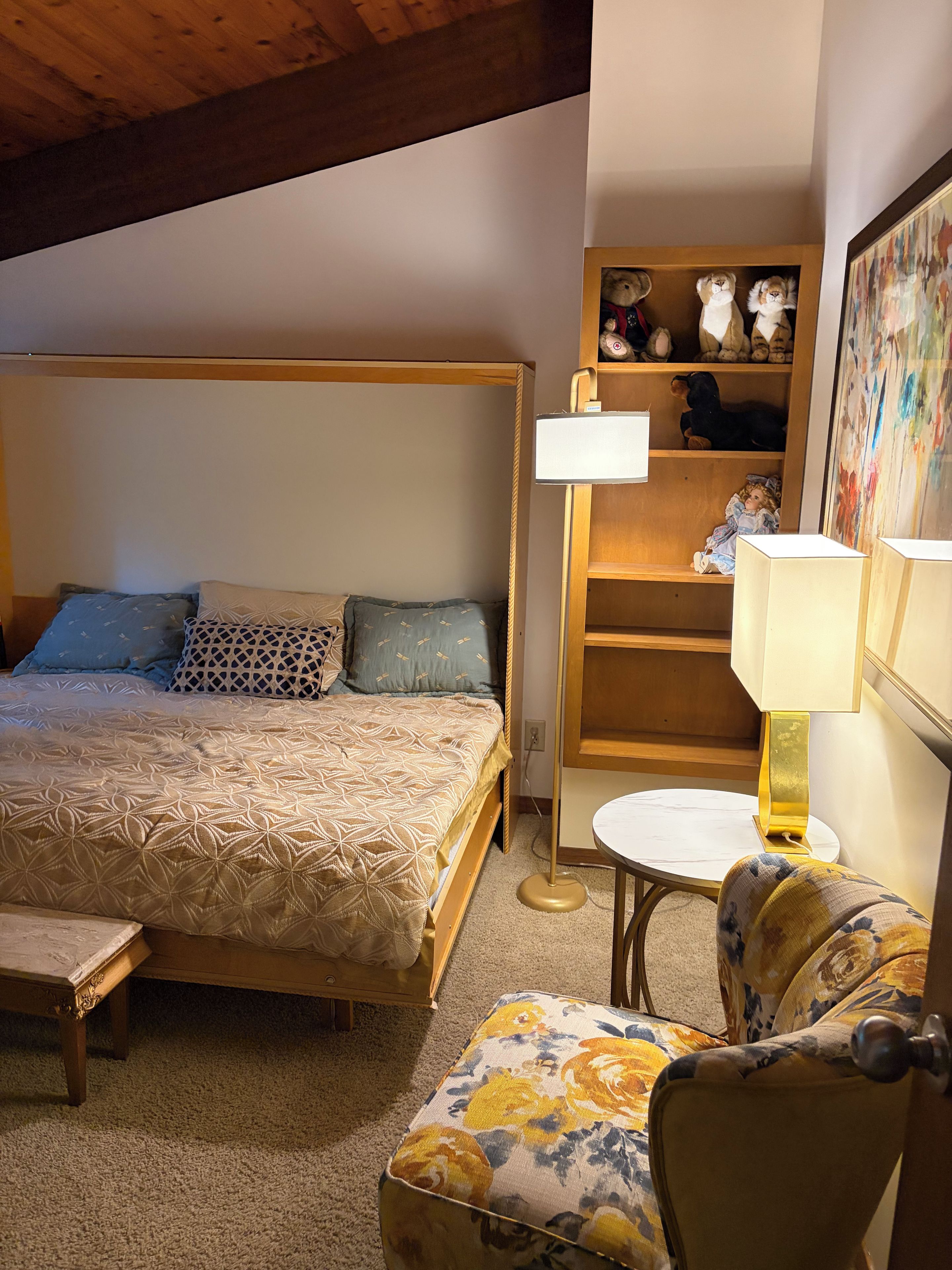 A bedroom with a bed, bedside table, lamp, and a chair.