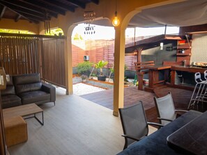 Eine Außenpatio mit Sitzgelegenheiten, einem Grillbereich und Blick auf einen Garten.