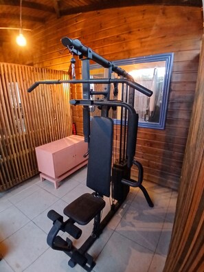 Ein Fitnessraum mit Trainingsgeräten, einer Bank und einem Spiegel an der Wand.