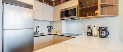 Een moderne keuken met roestvrijstalen apparatuur, een marmeren aanrecht en houten planken.