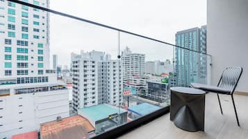 A balcony with a view of a cityscape, a round table, and a chair.