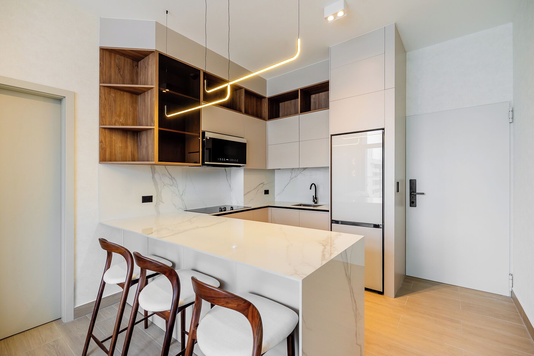 Een moderne keuken met een marmeren aanrechtblad, houten kastjes en een ingebouwde magnetron.
