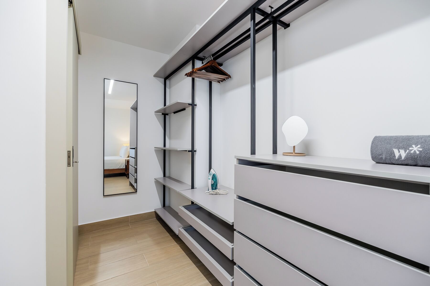 Un baño moderno con tocador, espejo y perchero.