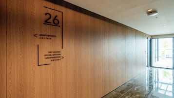 A hallway with a wooden wall, a number '26' sign, and directional arrows to amenities like 'Sky Lounge' and 'Social Kitchen'.