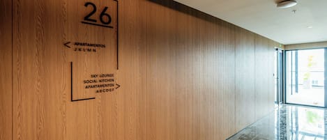 A hallway with a wooden wall, a number '26' sign, and directional arrows to amenities like 'Sky Lounge' and 'Social Kitchen'.