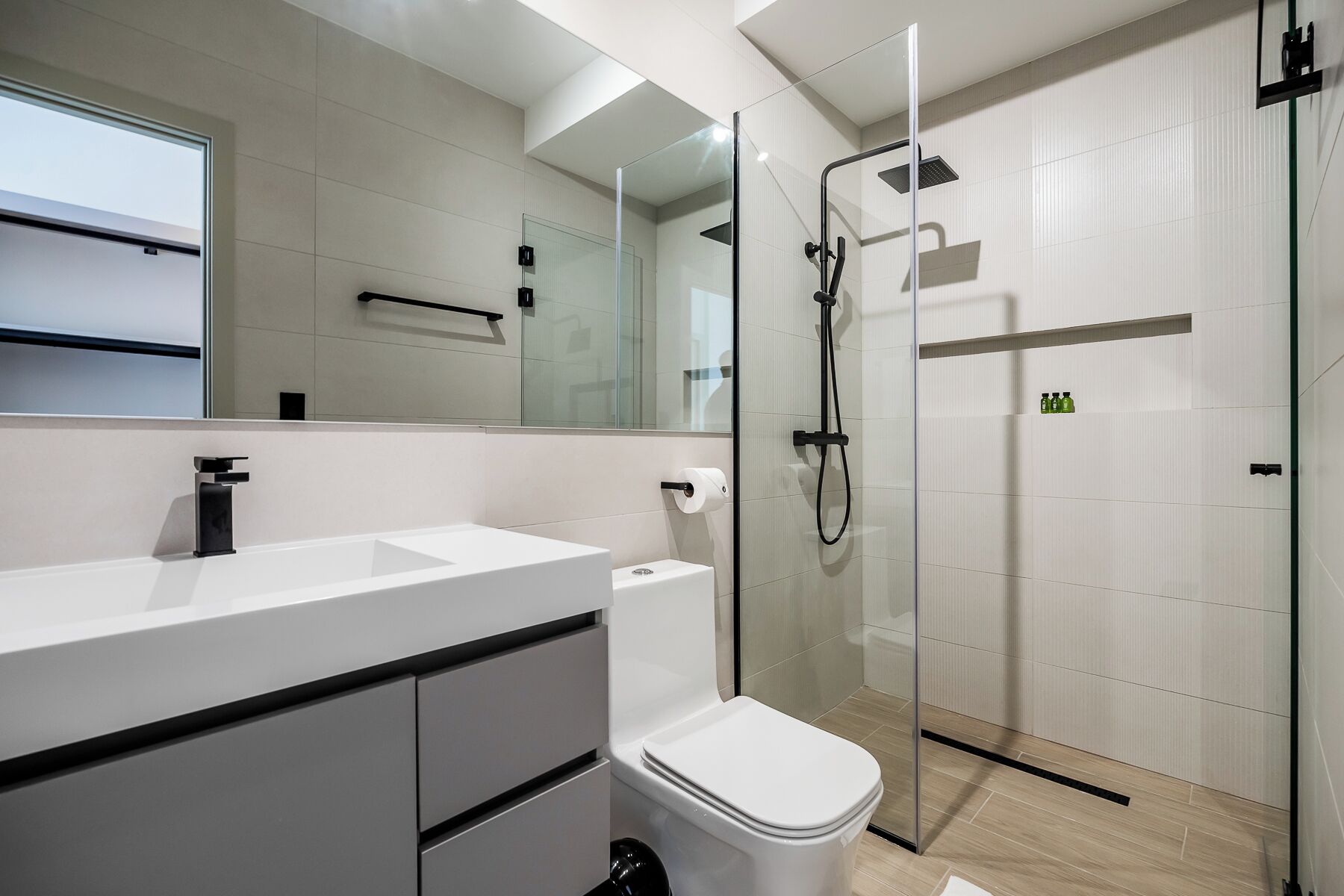 A modern bathroom with a glass shower enclosure, a white sink, and a toilet.
