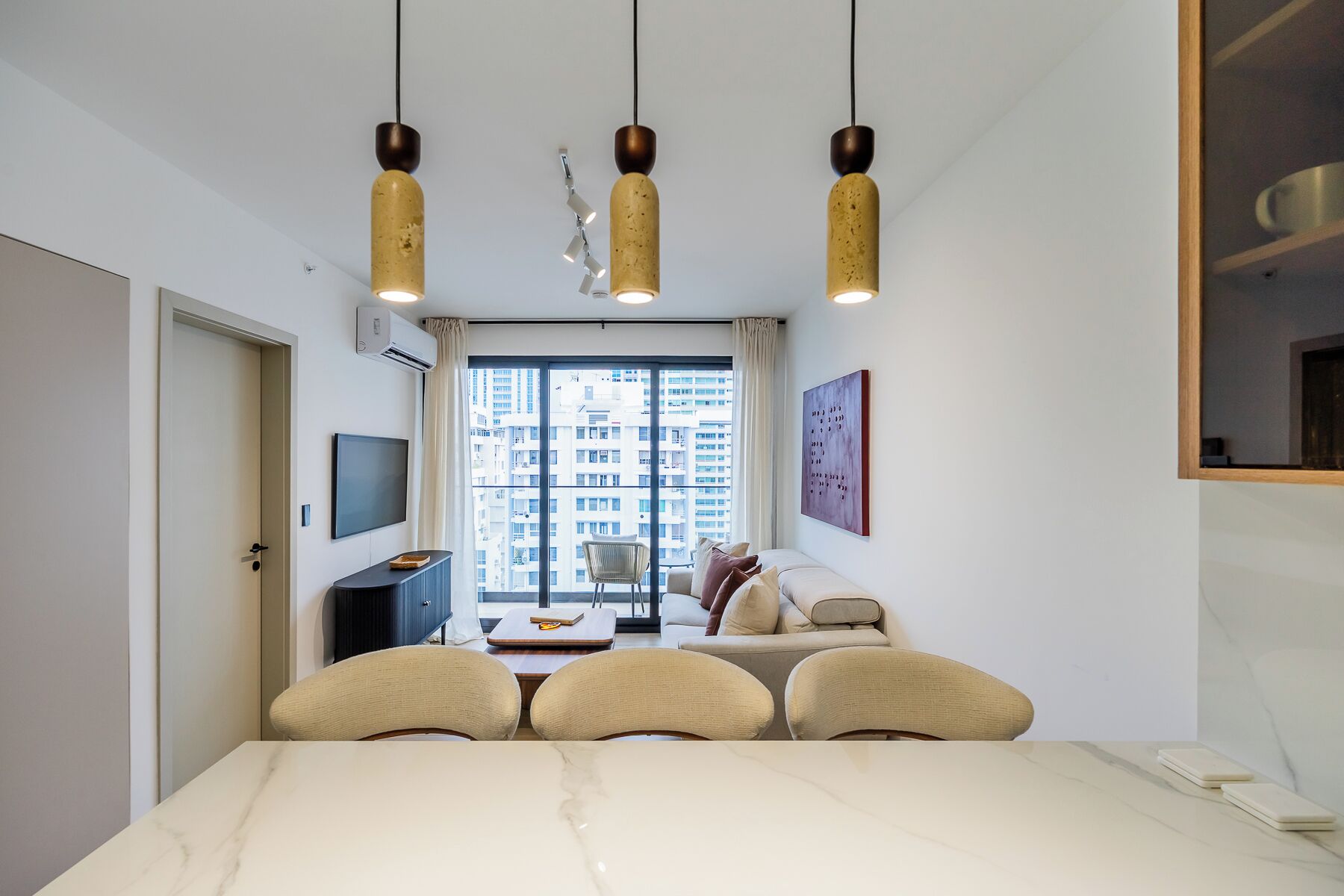 Ein modernes Hotelzimmer mit großem Fenster, Essbereich und einer Couch.