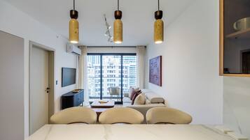 Ein modernes Hotelzimmer mit großem Fenster, Essbereich und einer Couch.