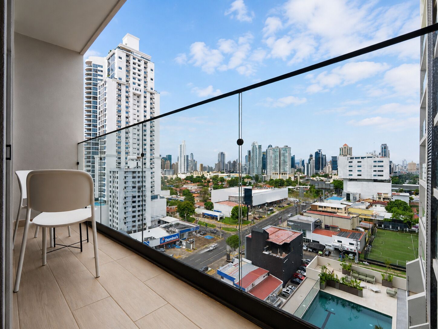 Un balcón con vistas a la ciudad, una silla y una zona de piscina.