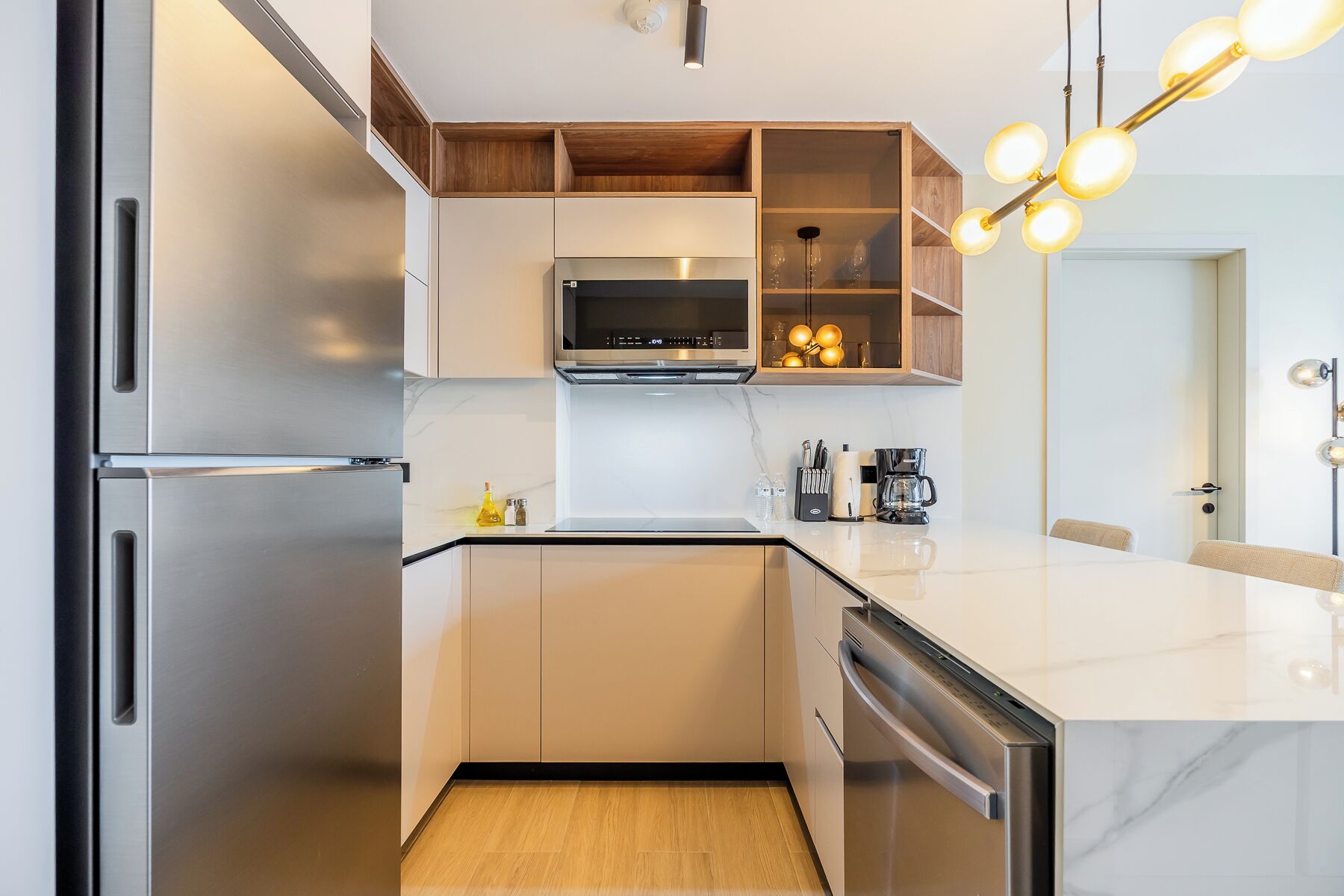 Una cocina moderna con electrodomésticos de acero inoxidable, estantes de madera y encimera de mármol.