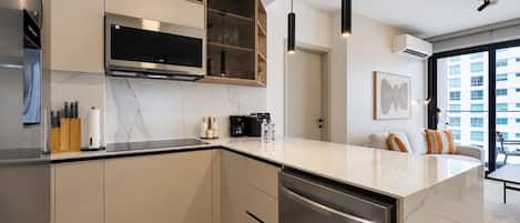 A modern kitchen with a built-in oven, microwave, and dishwasher, wooden cabinets, and pendant lighting.