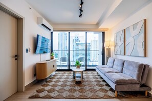 A modern living room with a sofa, a coffee table, and a TV on the wall. - The Hub Modern Apartments by Wynwood (Panamá)