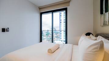 Habitación de hotel con una cama grande, una ventana con vista a la ciudad y un aire acondicionado instalado en la pared.