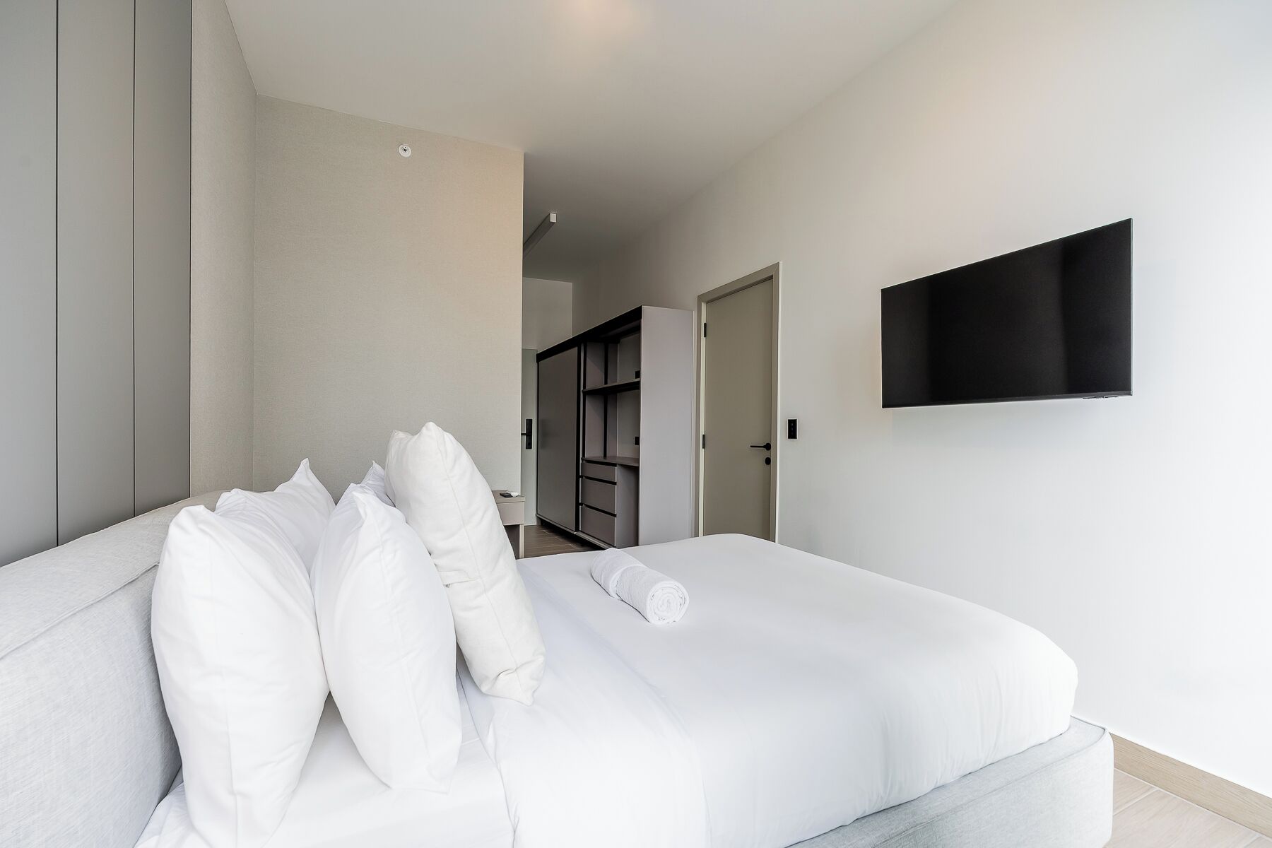Una moderna camera d'albergo con un letto, una TV a schermo piatto montata al muro e un armadio a muro.