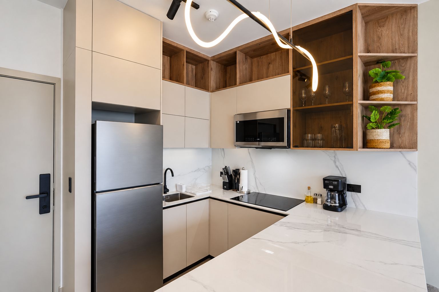 Una cocina moderna con un refrigerador de acero inoxidable, un microondas y una cafetera.