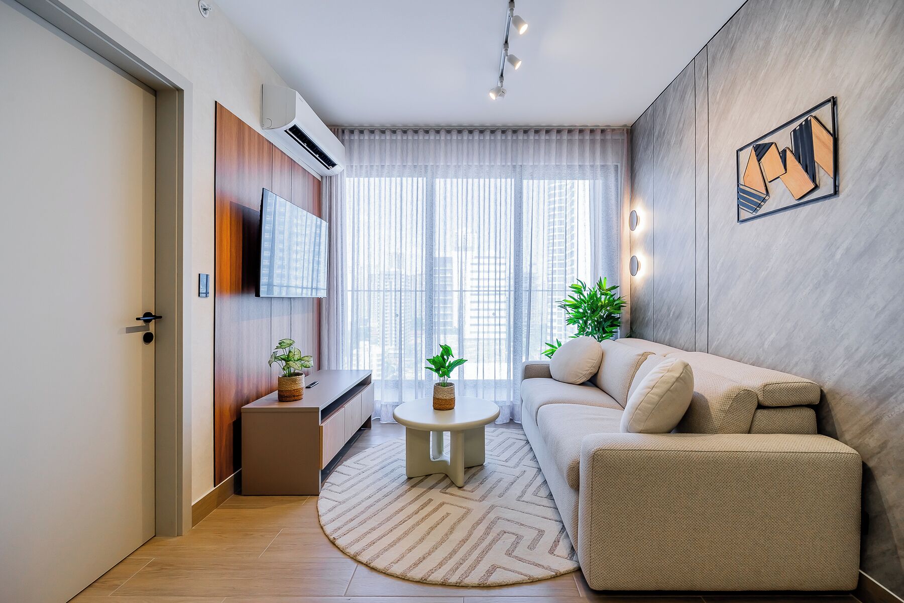 Ein modernes Wohnzimmer mit einer Couch, einem kleinen runden Tisch und einem Fernseher.