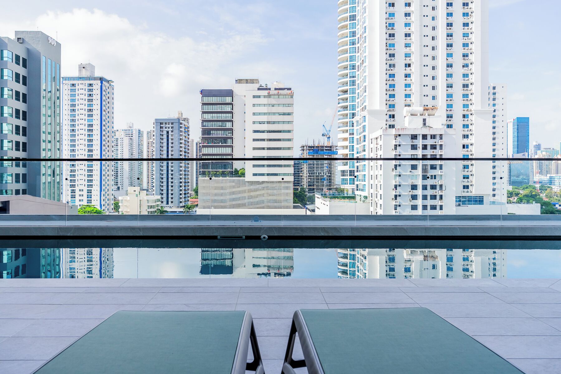 Un espace piscine sur le toit, avec des chaises longues et une vue sur la ville.
