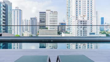 Un espace piscine sur le toit, avec des chaises longues et une vue sur la ville.