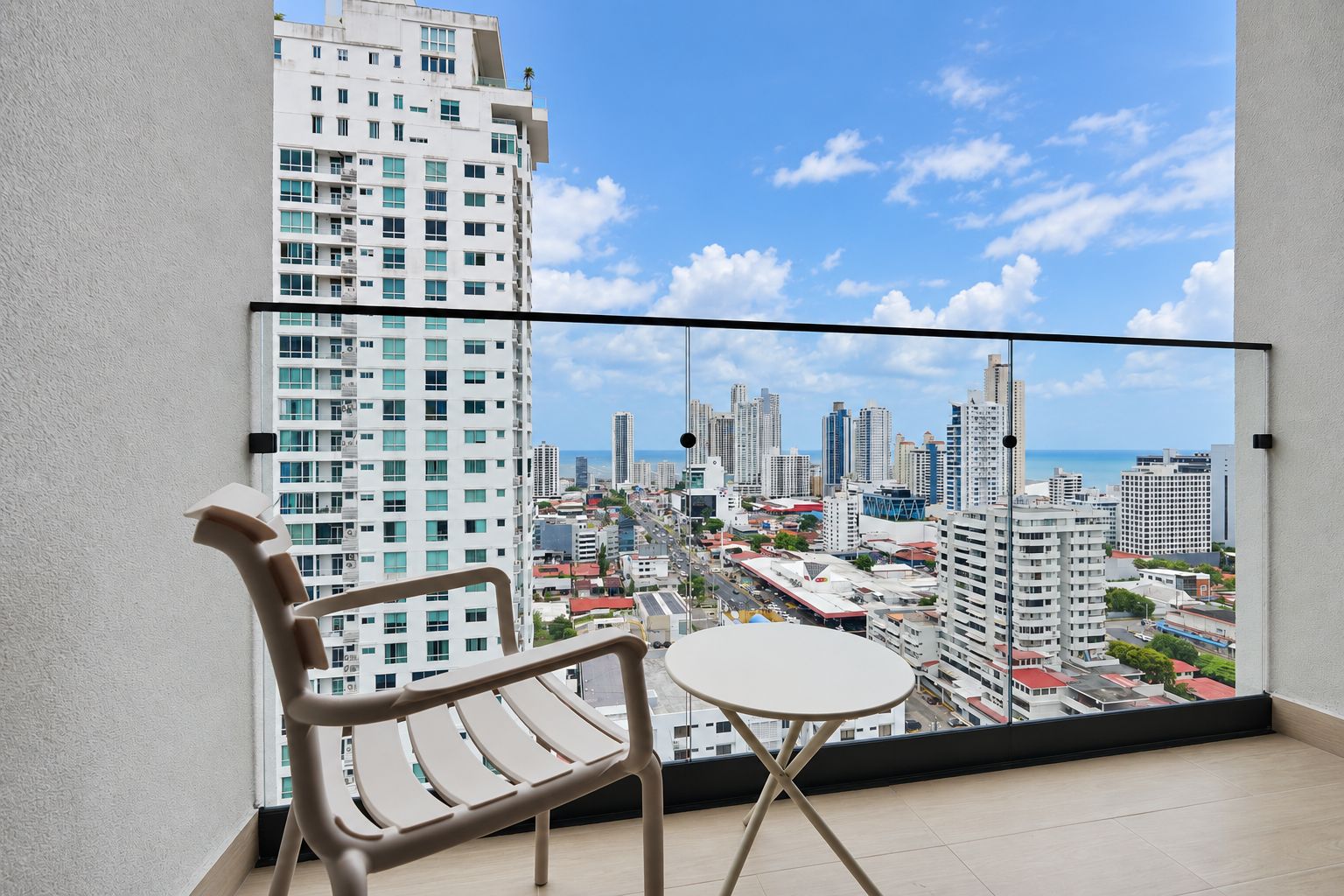 Un balcón con vistas a un paisaje urbano, una silla y una mesita.
