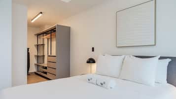 A hotel room with a bed, a nightstand, a lamp, a wardrobe, and a wall-mounted artwork.