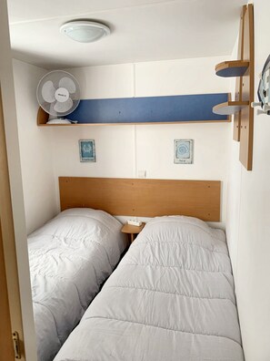 Una camera da letto con due letti, una ventola a soffitto e uno scaffale con oggetti decorativi.