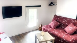 Un salon moderne avec un téléviseur à écran plat fixé au mur, une fenêtre offrant une belle vue, un canapé agrémenté de coussins à motifs et une petite table sur laquelle est posée une bougie.