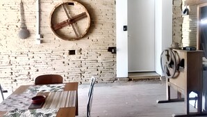 Une pièce avec un mur en briques, un tonneau en bois, une porte blanche et une table avec des chaises.