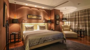Habitación de hotel con una cama grande, una zona de estar y vistas a la ciudad.