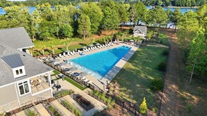Ein Pool mit Liegestühlen und Sonnenschirmen, umgeben von Bäumen und einem Haus.