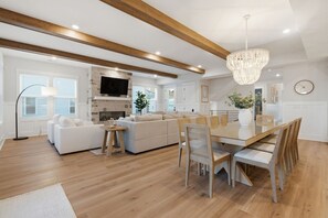 A modern kitchen with a dining area, wooden beams, a chandelier, and a flat-screen TV. - Luxury New Build with Lake Norman Views & Resort Amenities- Sleeps 16 (Lake Norman of Catawba)