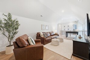 Ein modernes Wohnzimmer mit einer braunen Ledersofa-Garnitur, einer Topfpflanze und einem Flachbildfernseher.