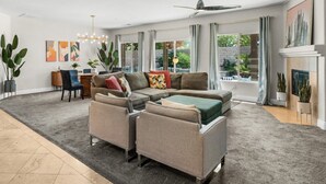 A modern living room with a sectional sofa, a dining area, and a fireplace. - Entire Home + Private Casita | Private Pool & Spa | Putting Green | Fully Fenced Yard| Community Amenities (Palm Springs)