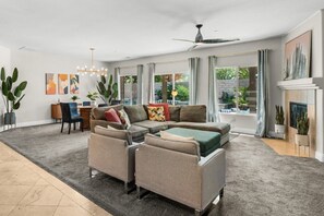 A modern living room with a sectional sofa, a dining area, and a fireplace. - Entire Home + Private Casita | Private Pool & Spa | Putting Green | Fully Fenced Yard| Community Amenities (Palm Springs)