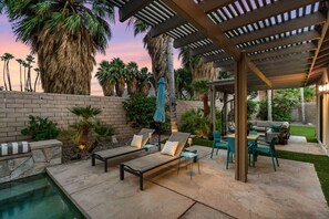 Un espace extérieur aménagé avec une piscine, des chaises longues et une pergola.