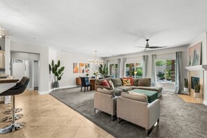 A spacious living room with a large sofa set, a dining area with a bar, and a kitchen in the background. - Entire Home + Private Casita | Private Pool & Spa | Putting Green | Fully Fenced Yard| Community Amenities (Palm Springs)