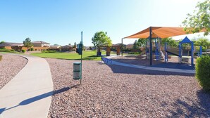 Ein Spielplatz mit schattigem Bereich und einem Weg dorthin.