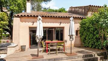 Un patio con tavolo e sedie, un barbecue e una zona relax coperta.