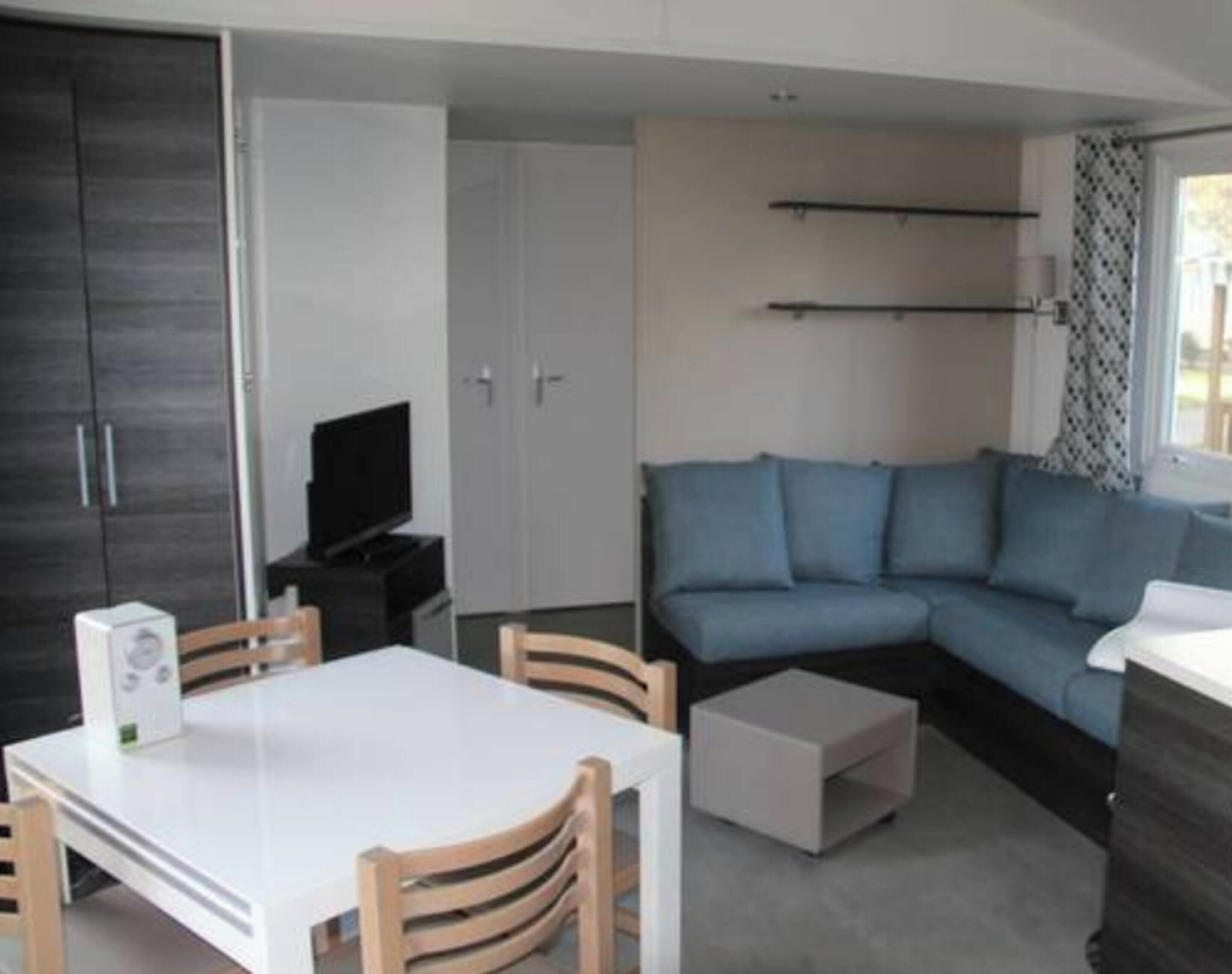A compact living space with a sofa, a TV, a dining table, and a small white cabinet.