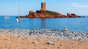 A coastal scene with a rocky island featuring a tower, boats, and a pebbly beach. - Homerez - Bungalow in Saint-Raphaël (Saint-Raphaël)