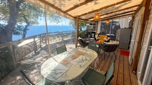 An outdoor dining area with a table, chairs, and a view of the sea. - Homerez - Bungalow in Saint-Raphaël (Saint-Raphaël)