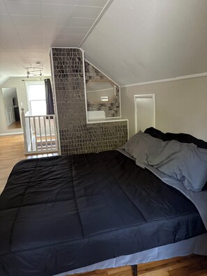 A bedroom with a large bed, a white ceiling, and a stone accent wall. - Large 3-bedroom house with AC in vibrant Minneapolis (Minneapolis)